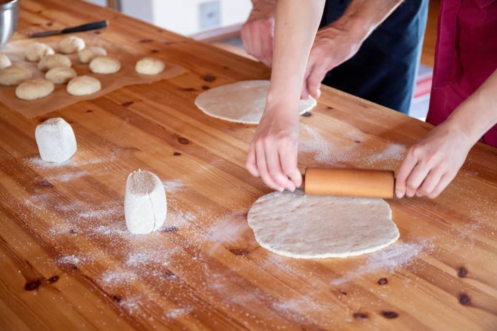 woman rolling and forming baking dough on kitchen table