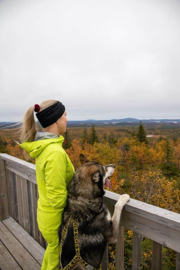 woman and husky dog looking over the forest