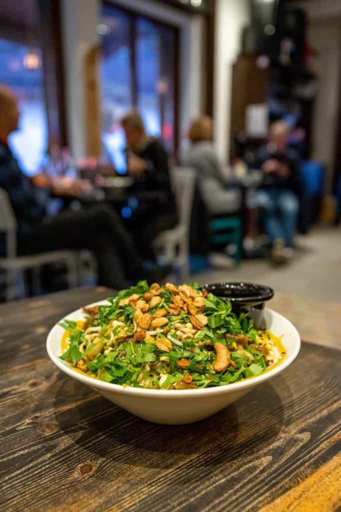 A salad with greens and nuts in a bowl.