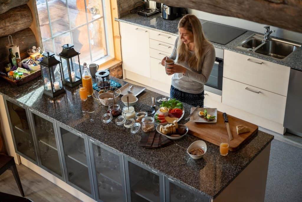 Woman standing in kitchen in front of breakfast dishes and foods on the counter