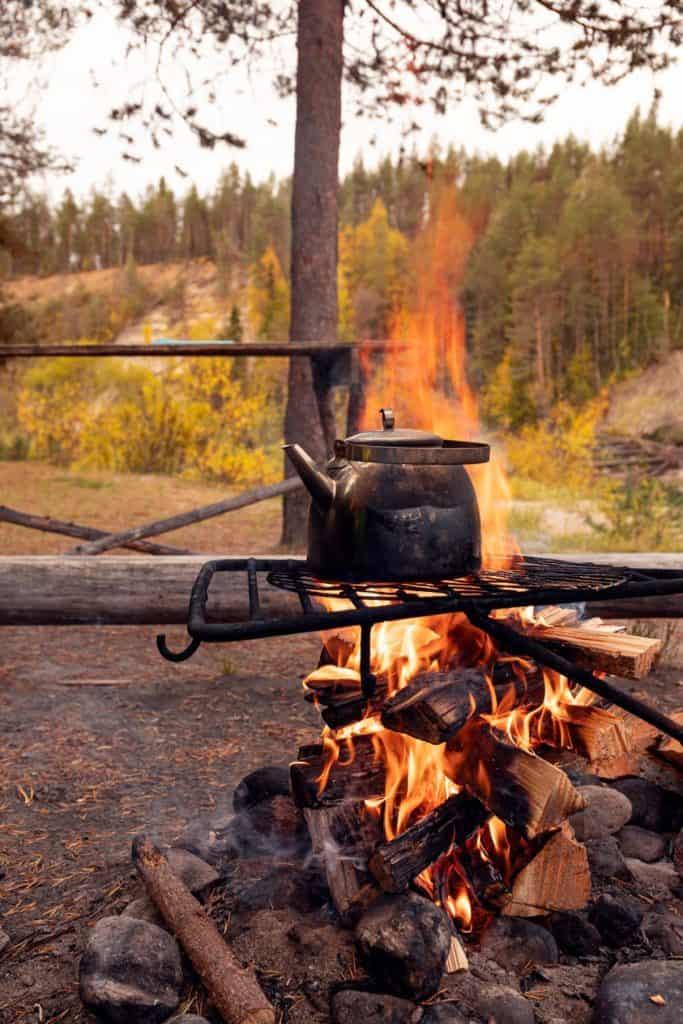 iron coffee kettle roasting over an outdoor campfire