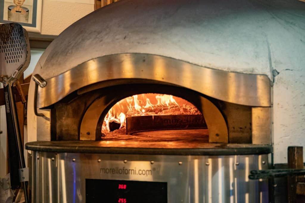 brick fire pizza oven with flames inside