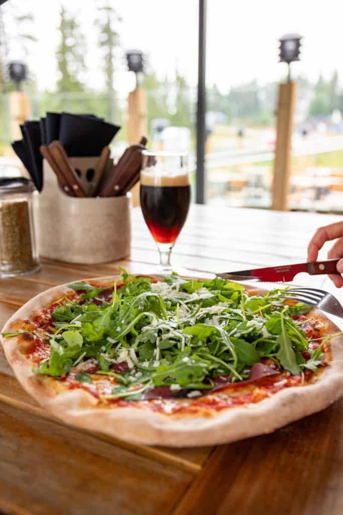 flat crust pizza with arugula, tomato sauce, and other toppings on it