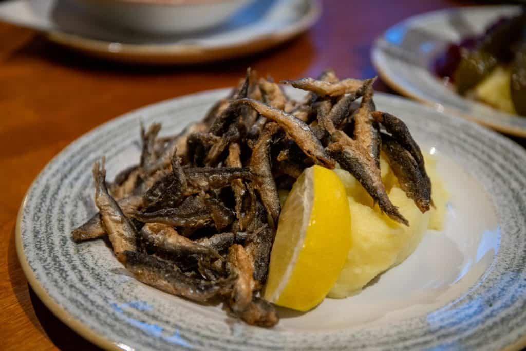 small fried vendace fish on top of mashed potatoes on a plate